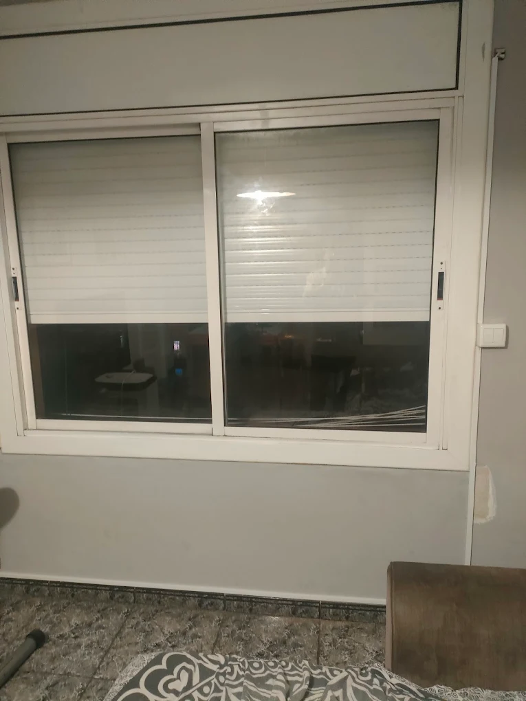 Persiana enrollable interior integrada en ventana corredera a medio bajar en vivienda de Barcelona – Persianas Camacho